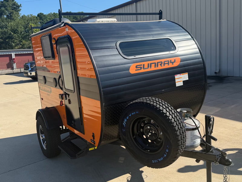  ready for your next travel or camping adventure.|This orange and black Sunray Sport teardrop RV rental is a compact camper with a roof rack and front-mounted spare tire.|This bright orange Sunray Sport teardrop trailer is ready for your RV rental adventure — photo 2