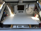 Compact RV rental outdoor kitchen in a teardrop trailer: features stove, spices, paper towels & organized storage for camping.