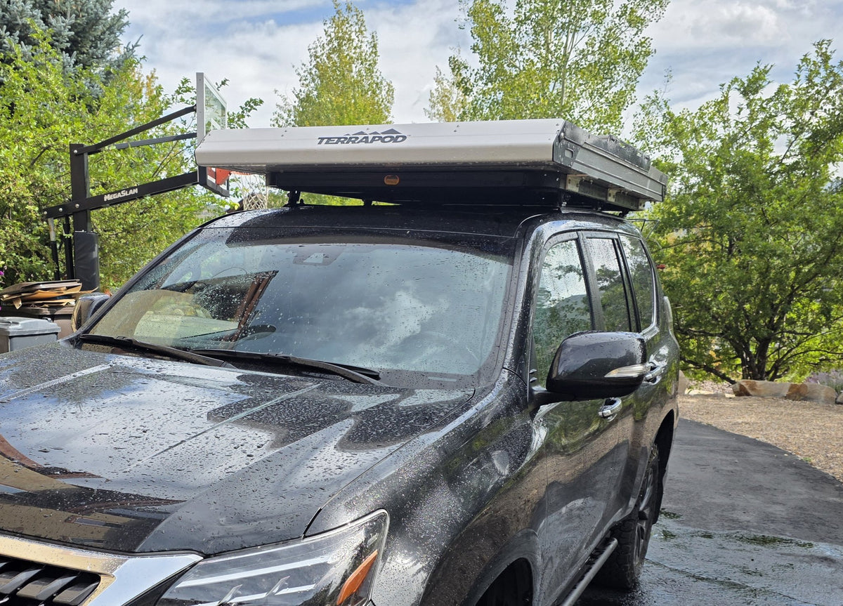 Side profile of the closed Terrapod RTTx XL on the roof rack with the TERRAPOD badge visible on the shell, showing how low and flat the hard shell sits when packed down — photo 5