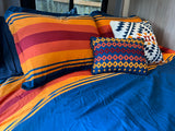 Cozy rv rental bedroom features vibrant striped bedding and Pendleton pillows, offering comfort in a compact interior space.
