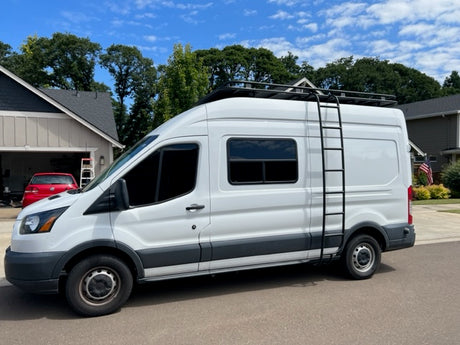White RV rental van with roof rack & ladder, perfect for your next road trip adventure.