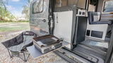 RV rental: Camper van featuring an outdoor griddle on a pull-out table, and a comfy camp chair for outdoor cooking.