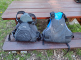 Two NRS PFDs (Ninja XXL, Ion XS/M) on a picnic table, essential water safety gear for your next rv rental trip.