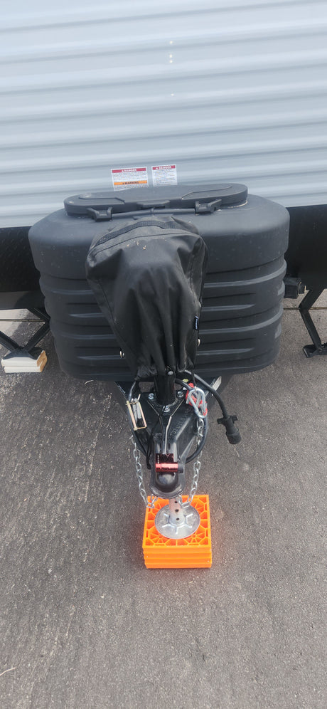 RV rental ready: The front hitch, covered propane tanks, safety chains, and jack stand on bright orange blocks.