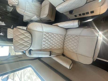 Luxury cream diamond-stitched seating inside an RV rental. Comfortable interior with black piping and visible seatbelts.