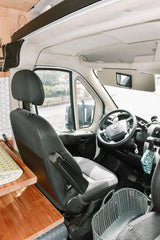 Spacious RV rental interior: driver's cabin with seat, steering wheel, dashboard, and glimpse of the living area.