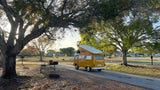 A classic yellow VW Westfalia camper van, perfect for an RV rental adventure, parked in a sunny campground.