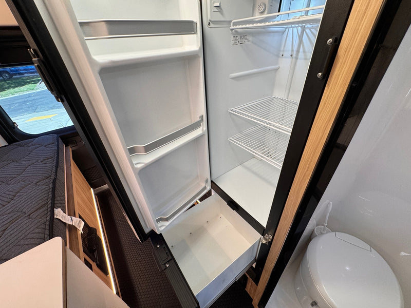 Inside an rv rental: an open refrigerator with freezer, a cozy bed, and toilet, highlighting a compact, functional space. — photo 19