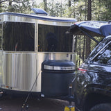 Experience outdoor travel with an RV rental. A shiny Airstream travel trailer and an SUV are parked at a peaceful wooded campsite.