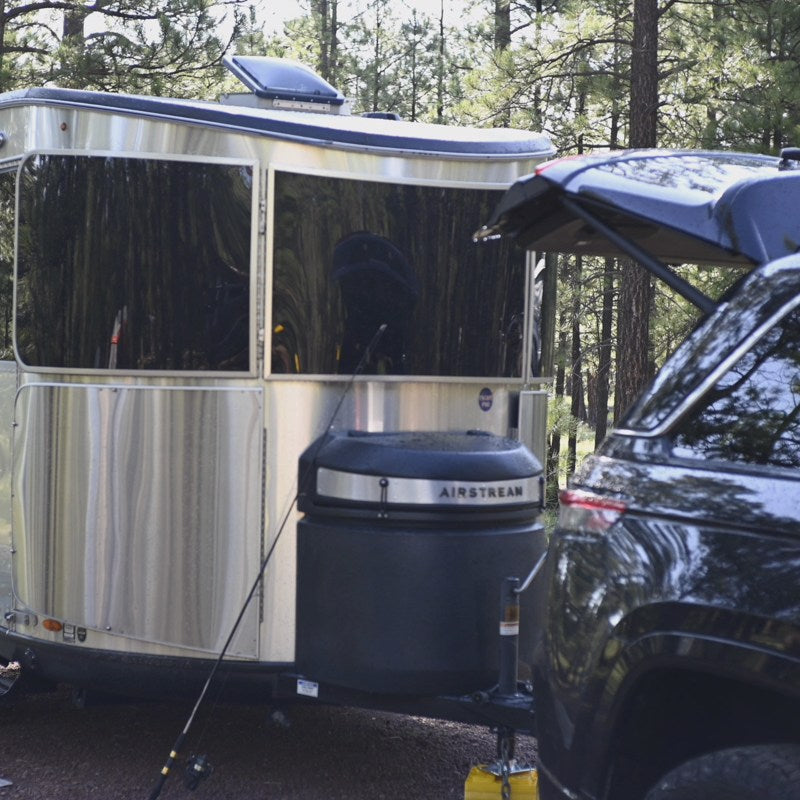 Experience outdoor travel with an RV rental. A shiny Airstream travel trailer and an SUV are parked at a peaceful wooded campsite. — photo 16