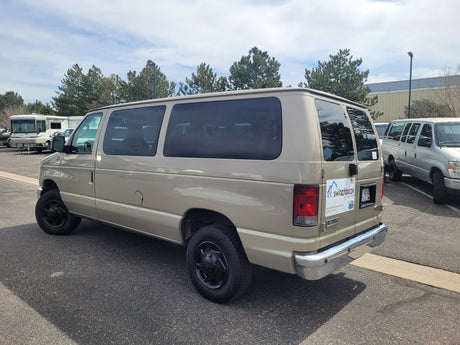 Switchback van rental's tan Ford E-350 in a parking lot, alongside an RV rental.