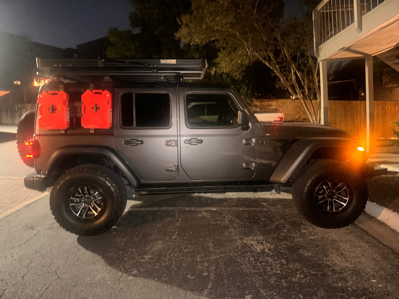  and rugged tires for off-roading adventures.|Night shot: Gray Jeep Wrangler with overland rooftop tent & Rotopax gear. Ideal for your next rv rental adventure.|This overland-ready grey Jeep Wrangler — photo 4