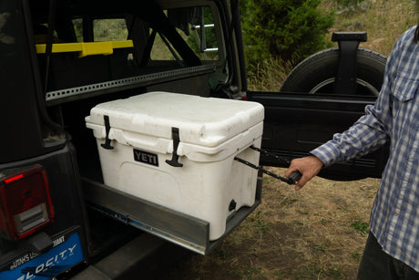 Organized Jeep adventure with an rv rental! Man pulls Yeti cooler from custom slide-out storage system.