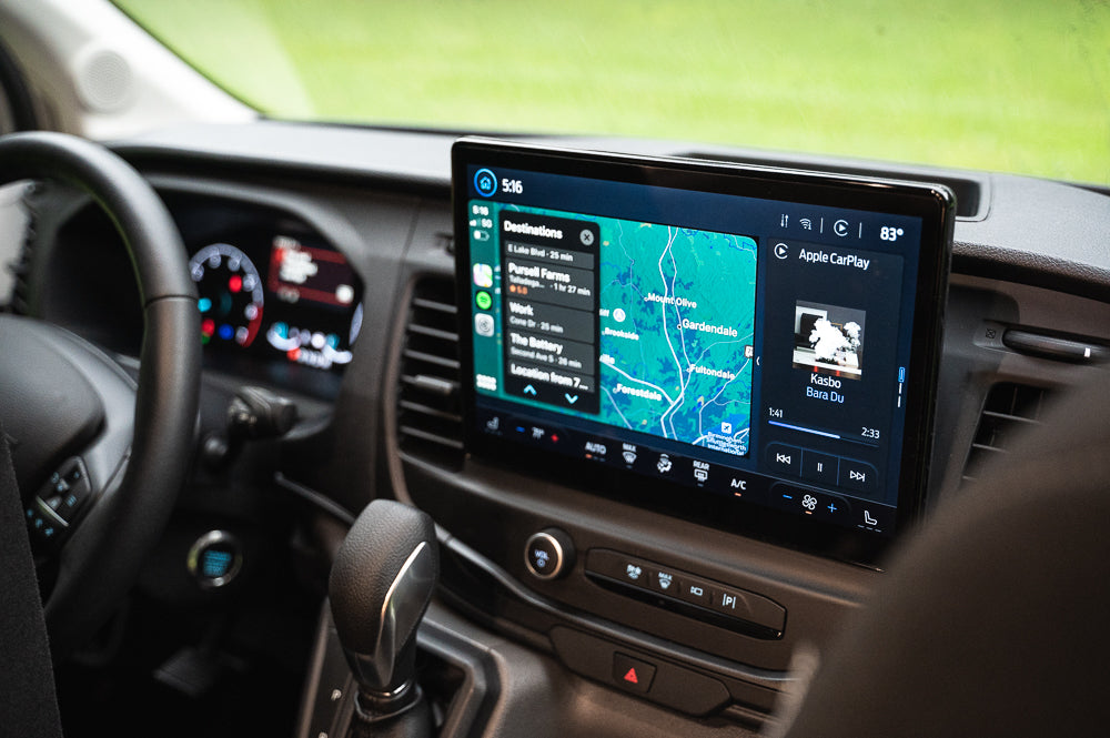 Inside an RV rental, the central screen shows Apple CarPlay, featuring a navigation map with destinations and current music playing.