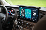 Inside an RV rental, the central screen shows Apple CarPlay, featuring a navigation map with destinations and current music playing.