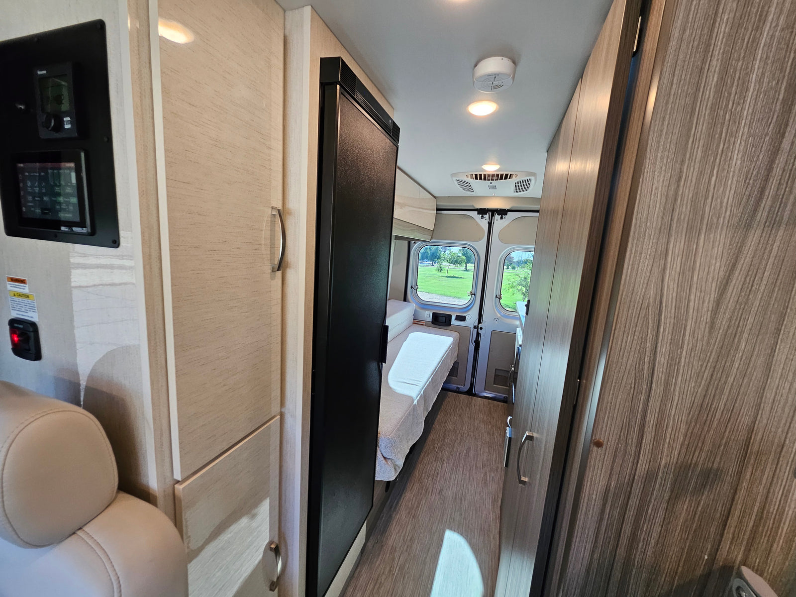 Step inside this RV rental! View of the bed, control panel, refrigerator, and ample storage for travel.