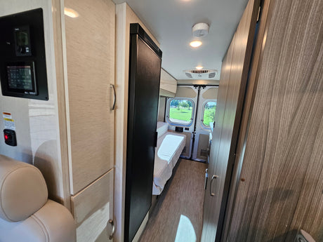 Step inside this RV rental! View of the bed, control panel, refrigerator, and ample storage for travel.