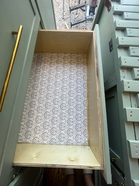 Smart RV rental storage: A custom sage green drawer with patterned liner, beside space-saving steps, offers tidy organization.