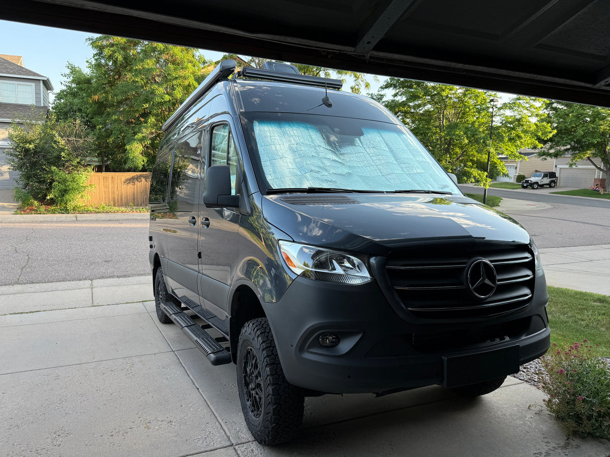 Dark gray Mercedes-Benz Sprinter camper van, perfect for rv rental adventures. Features off-road tires, running boards, and a roof awning. — photo 11
