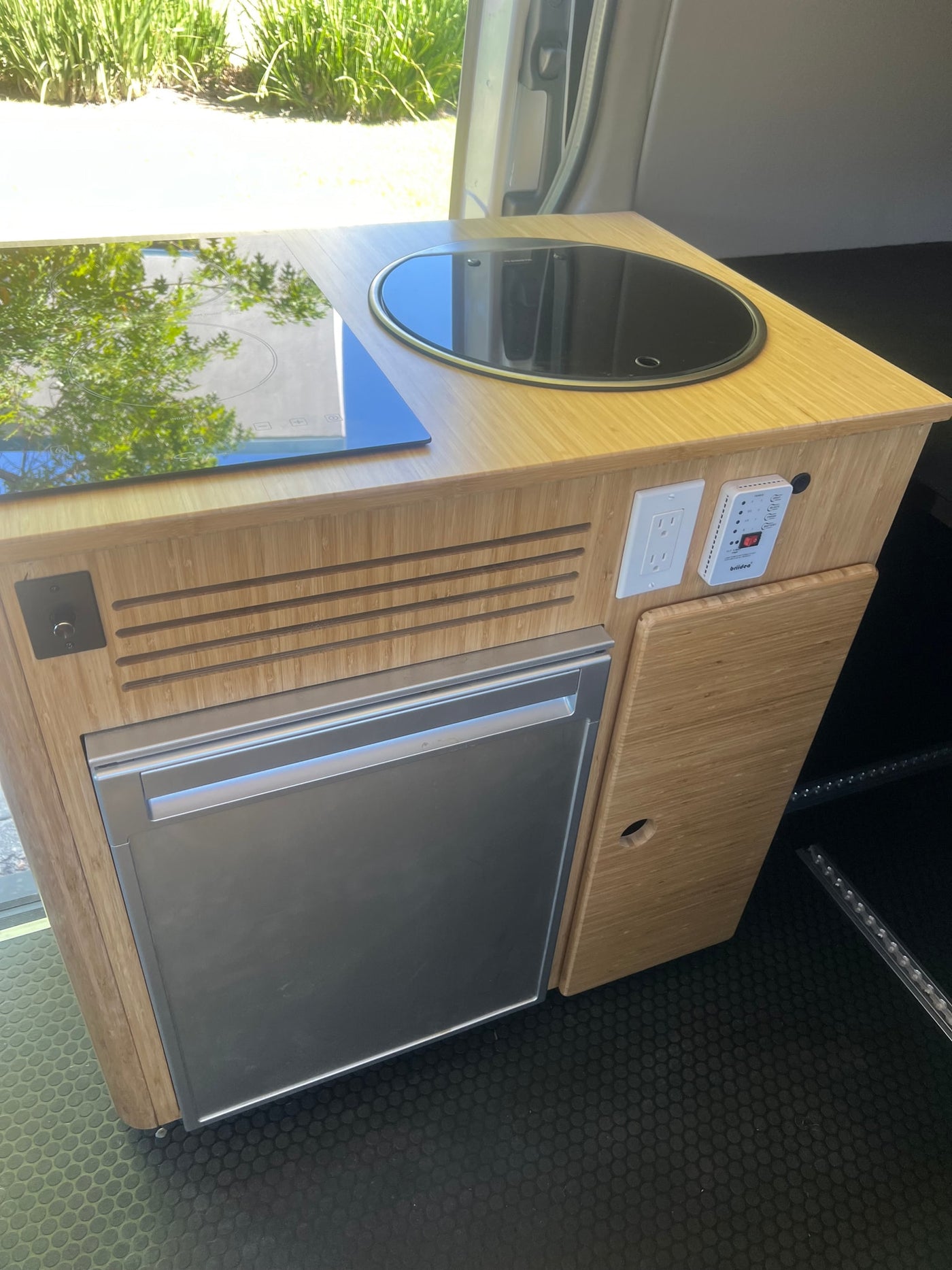RV rental: Compact kitchen unit with induction cooktop, sink, and fridge. Features bamboo wood finish and controls. — photo 6