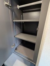 RV rental: View inside a small, grey cabinet with a white hanging rod, two adjustable shelves, and visible door hinges.