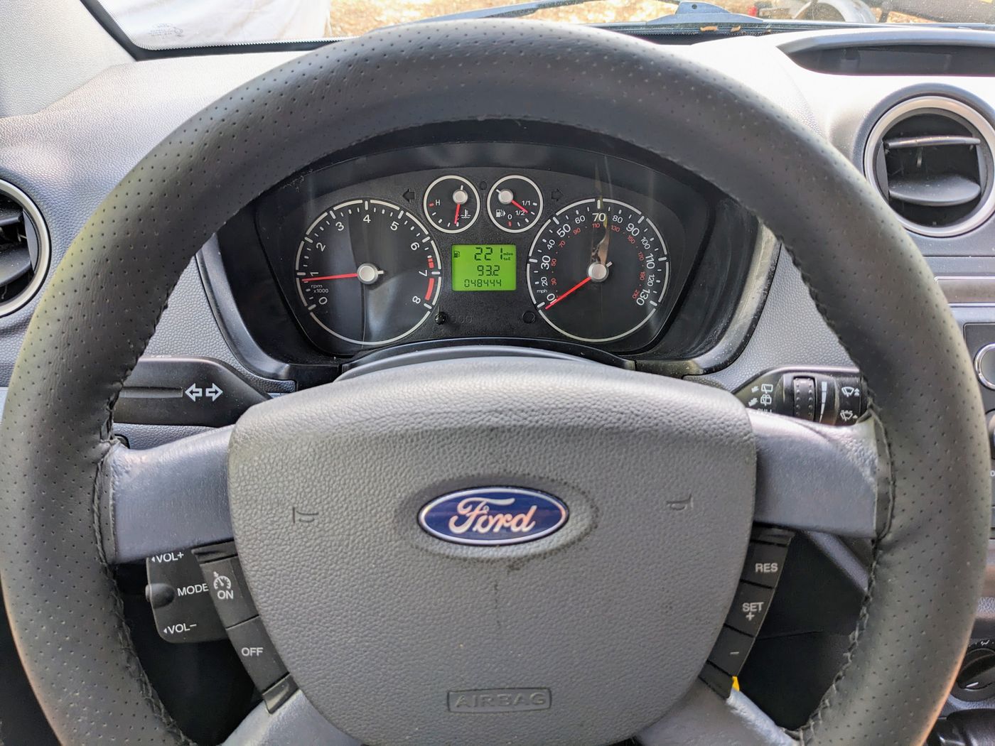Interior view of a Ford car dashboard with steering wheel, instruments, and 048444 odometer. Great for an RV rental trip.