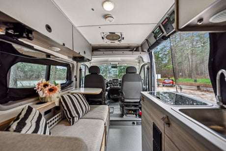 Spacious RV rental interior with kitchen, living area, and cockpit. Scenic outdoor views from windows.