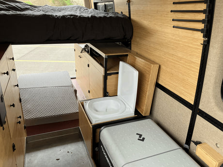 RV rental: Smart camper van interior features an elevated bed, pull-out toilet, and portable fridge, maximizing space.