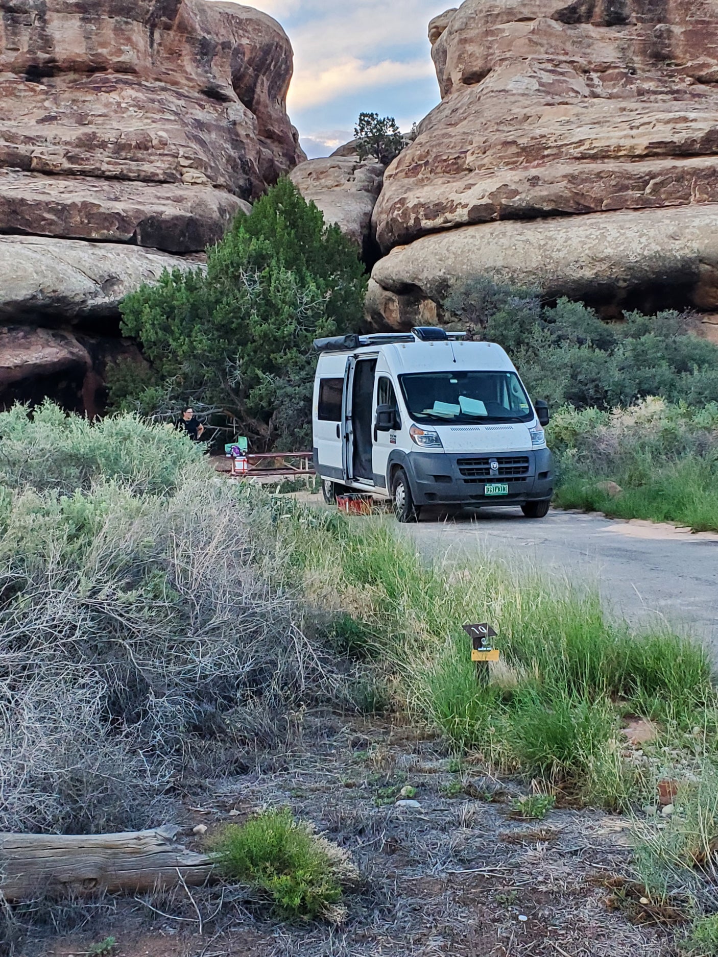 White RV rental at campsite 10, nestled between towering rock formations and green shrubbery. Great for outdoor adventures.