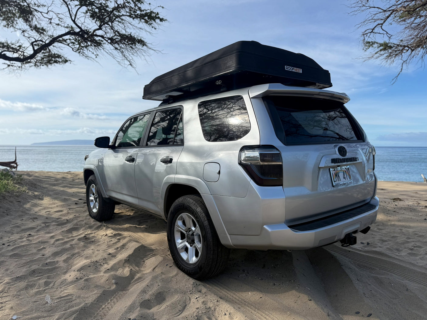 Silver 4Runner with a rooftop tent parked on a sandy Hawaiian beach. This overlanding rv rental is ready for adventure!
