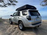 Silver 4Runner with a rooftop tent parked on a sandy Hawaiian beach. This overlanding rv rental is ready for adventure!