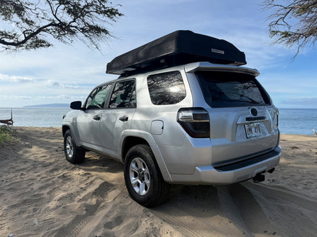 Silver 4Runner with a rooftop tent parked on a sandy Hawaiian beach. This overlanding rv rental is ready for adventure!