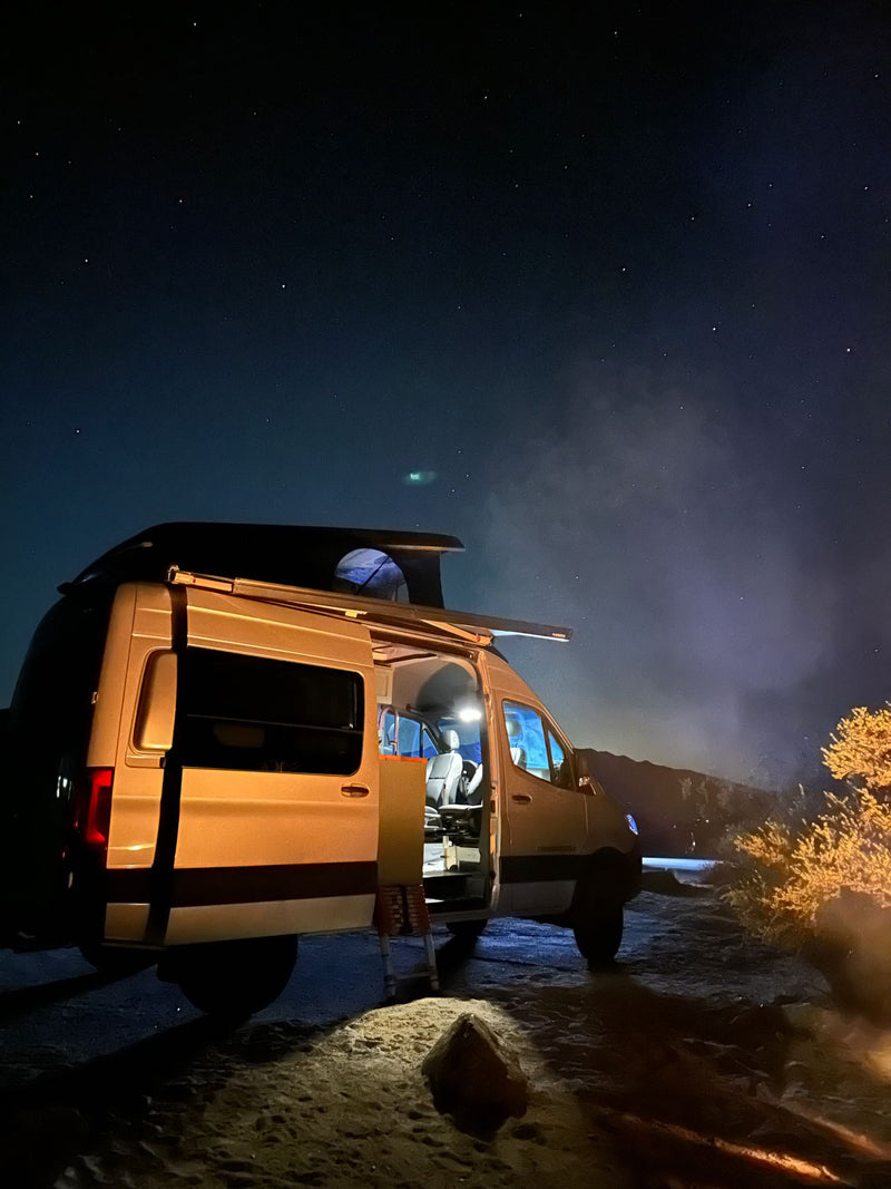 Stargazing from an RV rental camper van with pop-top. Interior lights glow under a clear — photo 1