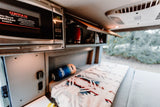 Experience comfort in your RV rental: Built-in microwave, ample storage, and a cozy bed with a soft blanket.