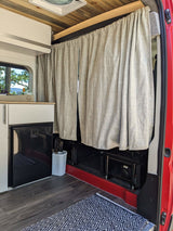 This rv rental features a compact kitchenette with fridge, privacy curtains, wood ceiling, and stylish flooring.