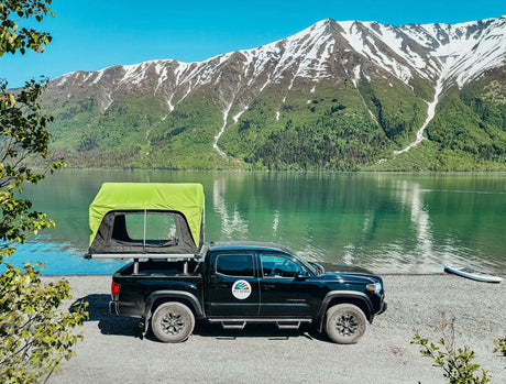 Adventure awaits! This **RV rental** truck with a rooftop tent offers lakeside **camping** with stunning mountain views. Perfect for outdoor travel.