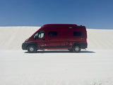 Red Winnebago Solis RV rental parked on white gypsum dunes under a clear blue sky, ready for desert adventure.
