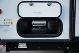 An RV rental's side with its main storage compartment open, revealing a green dragon-shaped hex key inside.