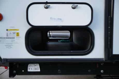 An RV rental's side with its main storage compartment open, revealing a green dragon-shaped hex key inside.