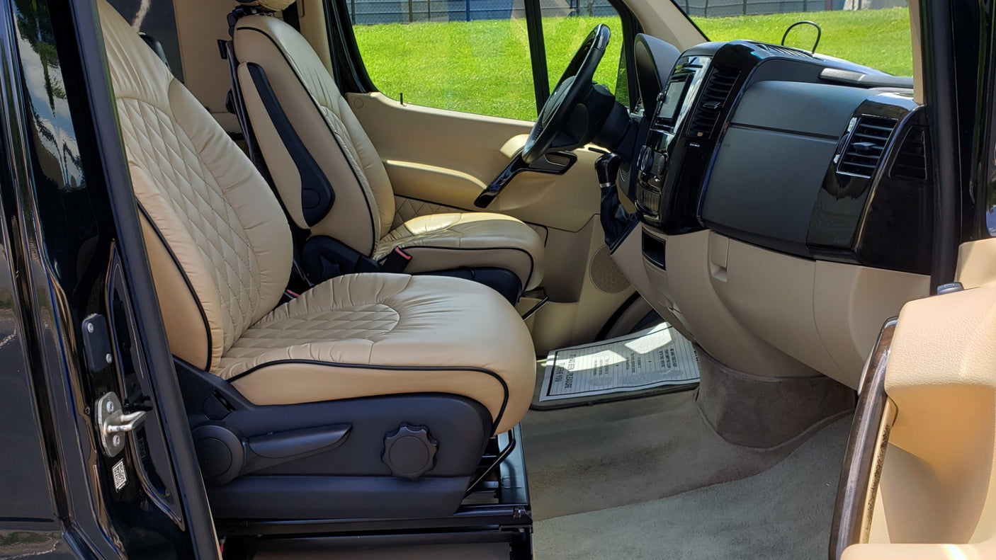 Step inside this luxurious RV rental: spacious interior with quilted tan leather seats and modern dashboard, ready for adventure.