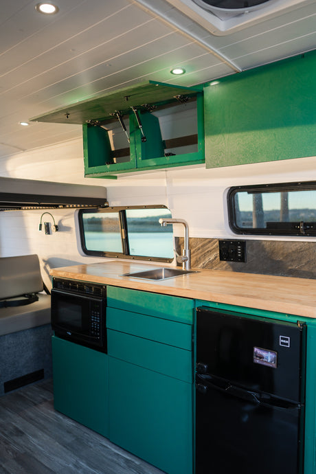 Explore in comfort: RV rental featuring a vibrant green custom kitchen with microwave, sink, and compact fridge.
