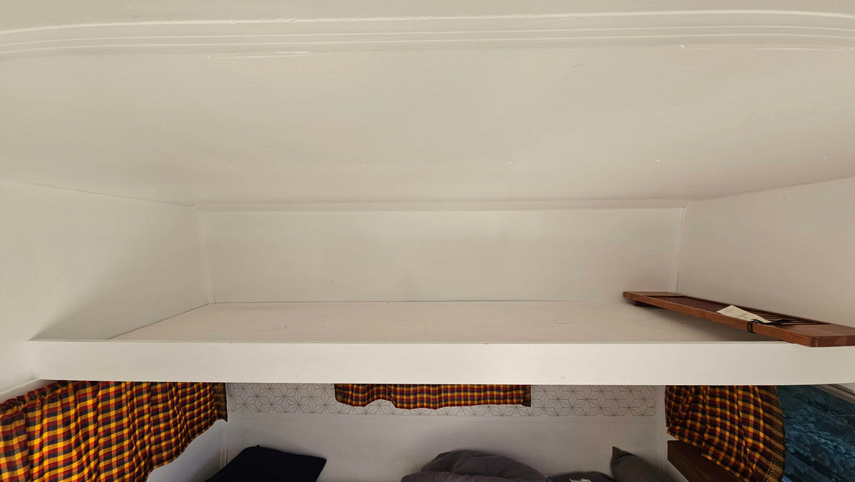 Cozy rv rental bunk bed area with plaid curtains & decorative wall pattern. Upper bunk has a wooden tray. — photo 8