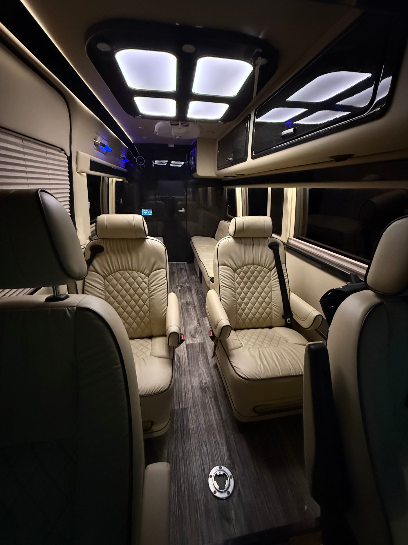 Luxurious RV rental interior: cream quilted seats, wood-look floor, and ample lighting for comfortable travel.