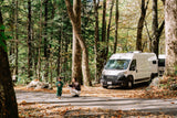 A family enjoys an autumn day with their RV rental parked in a serene forest, surrounded by vibrant fall foliage.