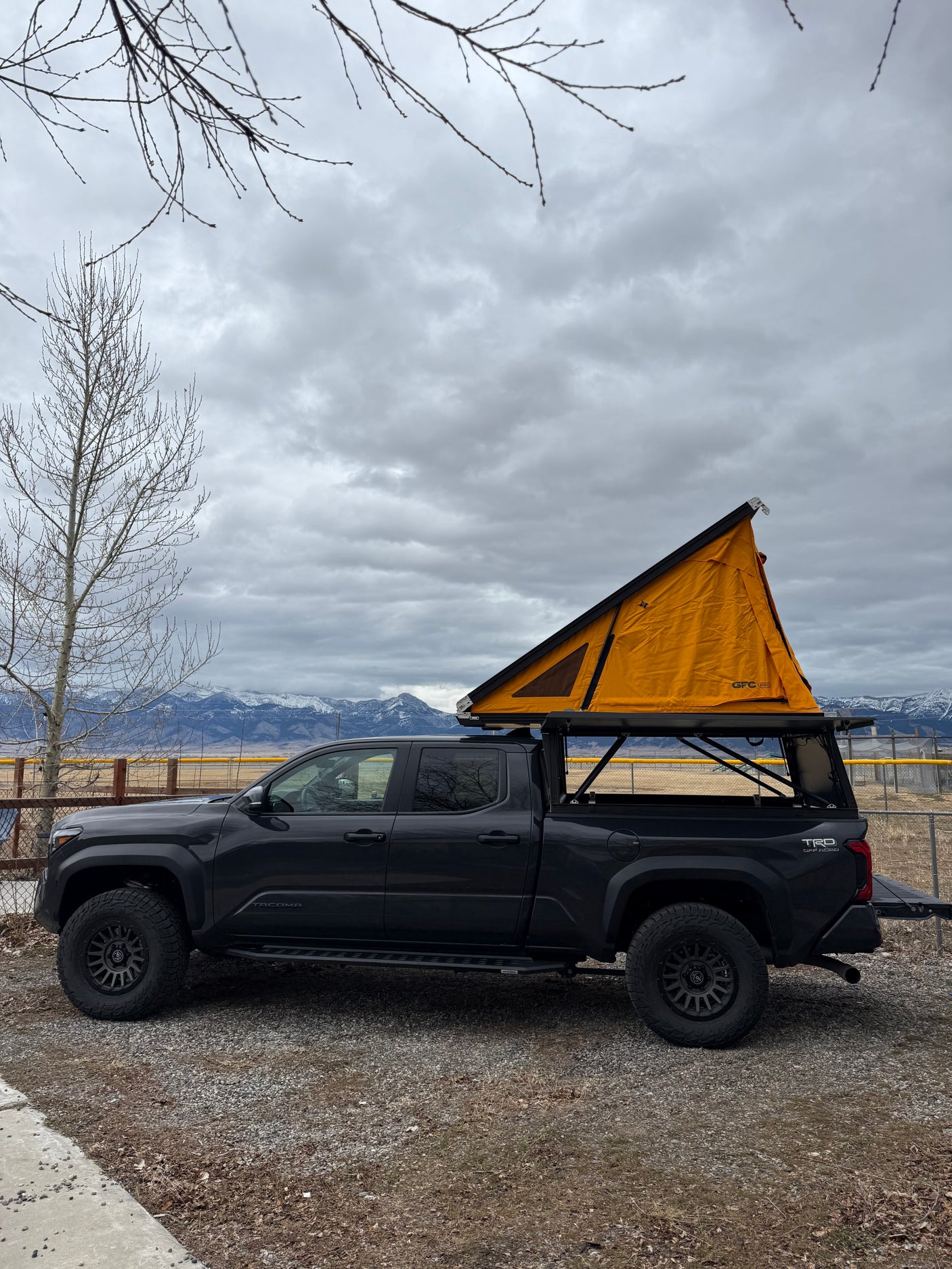 Dark grey Toyota Tacoma overland truck with orange rooftop tent. Great for camping, an alternative to an RV rental adventure.