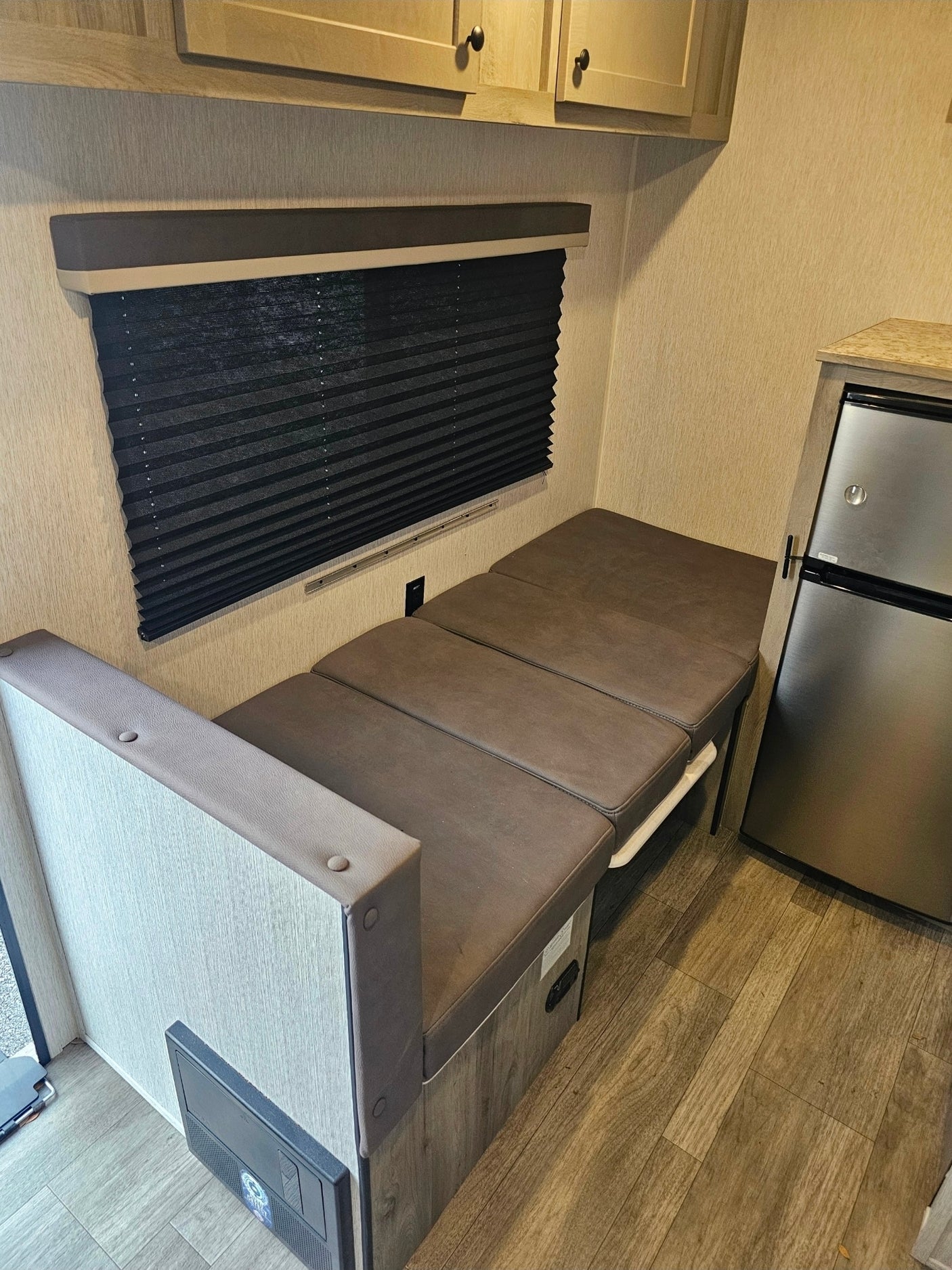 This RV rental features a versatile dinette that converts into a bed, with a window and fridge, optimizing small space living.