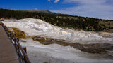 Explore Yellowstone's Mammoth Hot Springs via RV rental, seeing stunning travertine terraces and boardwalks under a blue sky.