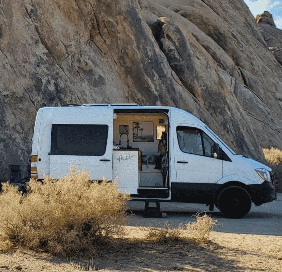 White camper van RV rental parked in a rocky desert landscape. Side door open, revealing a cozy interior for outdoor adventures. — photo 2
