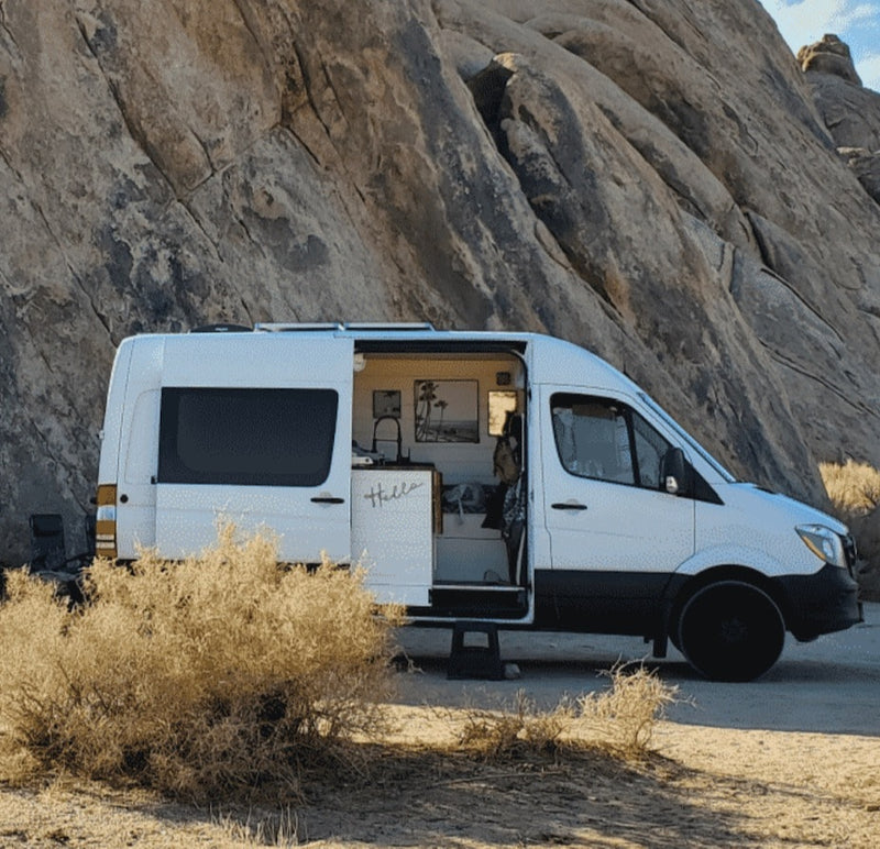 White camper van RV rental parked in a rocky desert landscape. Side door open, revealing a cozy interior for outdoor adventures. — photo 2