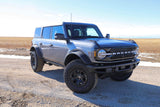 Gray Ford Bronco 4-door on a dirt road in a field, perfect for outdoor trips. An adventurous alternative to an RV rental.